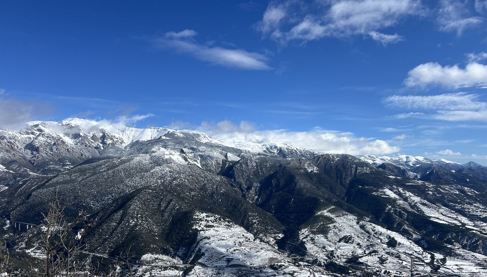 La serralada nevada sobre la vall, amb el poble i els camps coberts de neu